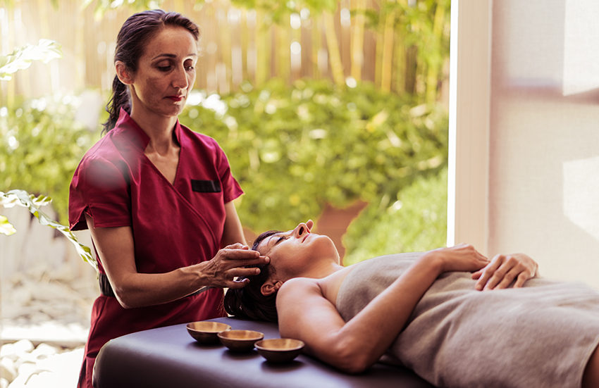 Thérapeute effectuant des pressions sur le  cuir chevelu d'une femme allongée sur le dos pour un shirodhara Alliance Pornic