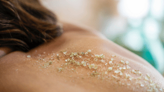 Femme allongée sur le ventre avec une main effectuant un gommage corps sur le dos Alliance Pornic